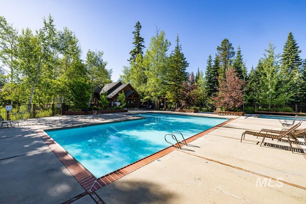 Community pool featuring a patio and view of scattered trees