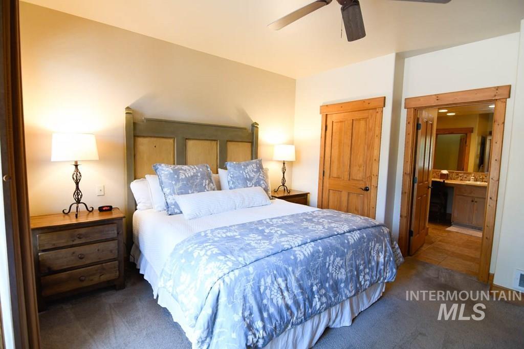 Bedroom featuring ensuite bath, carpet, and a ceiling fan