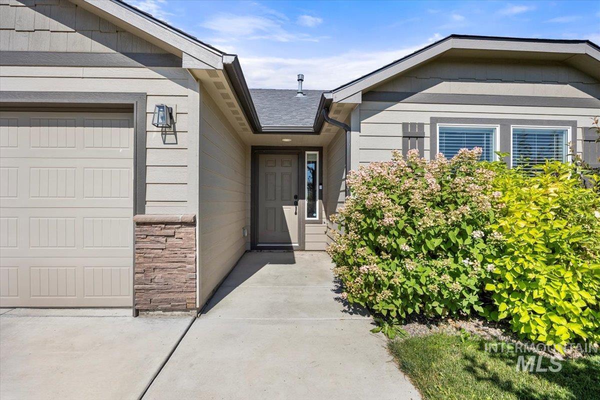 Entrance to property featuring stone siding and an attached garage