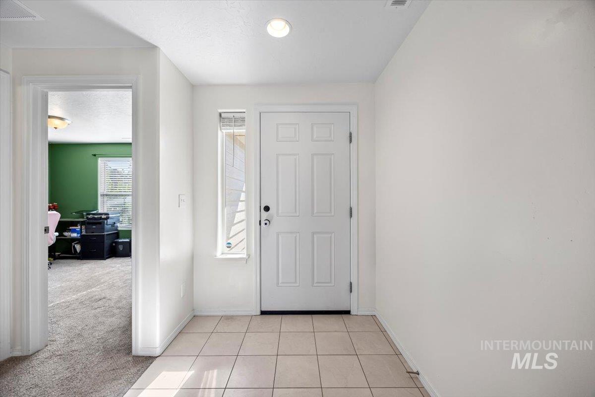 Entrance foyer featuring light tile patterned flooring, light colored carpet, and a textured ceiling