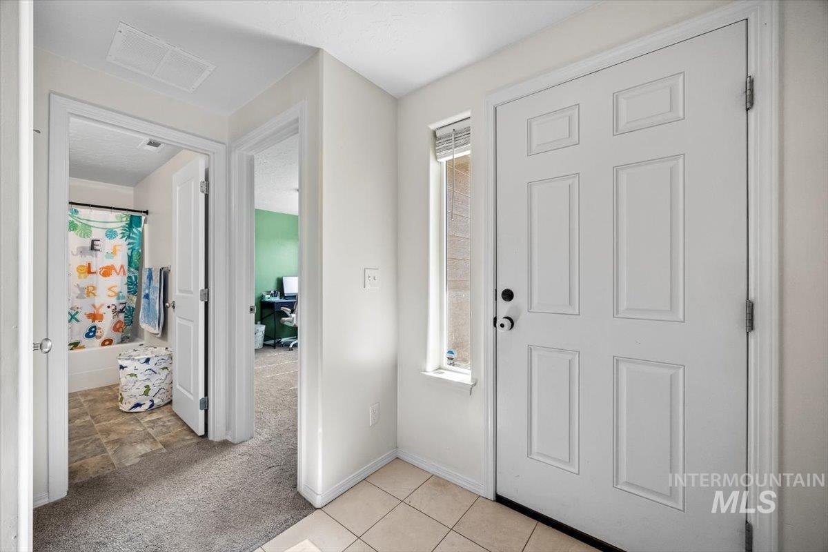 Foyer entrance featuring light carpet and light tile patterned flooring