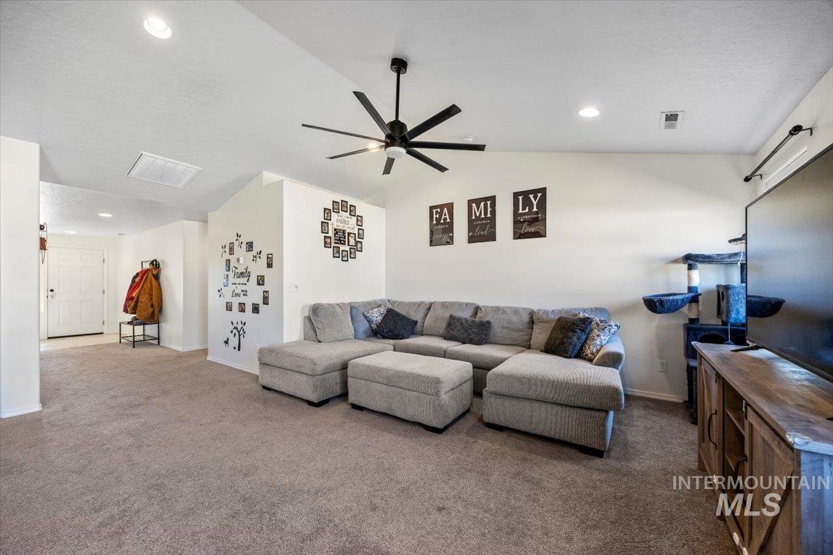 Carpeted living room featuring vaulted ceiling, recessed lighting, a ceiling fan, and a textured ceiling