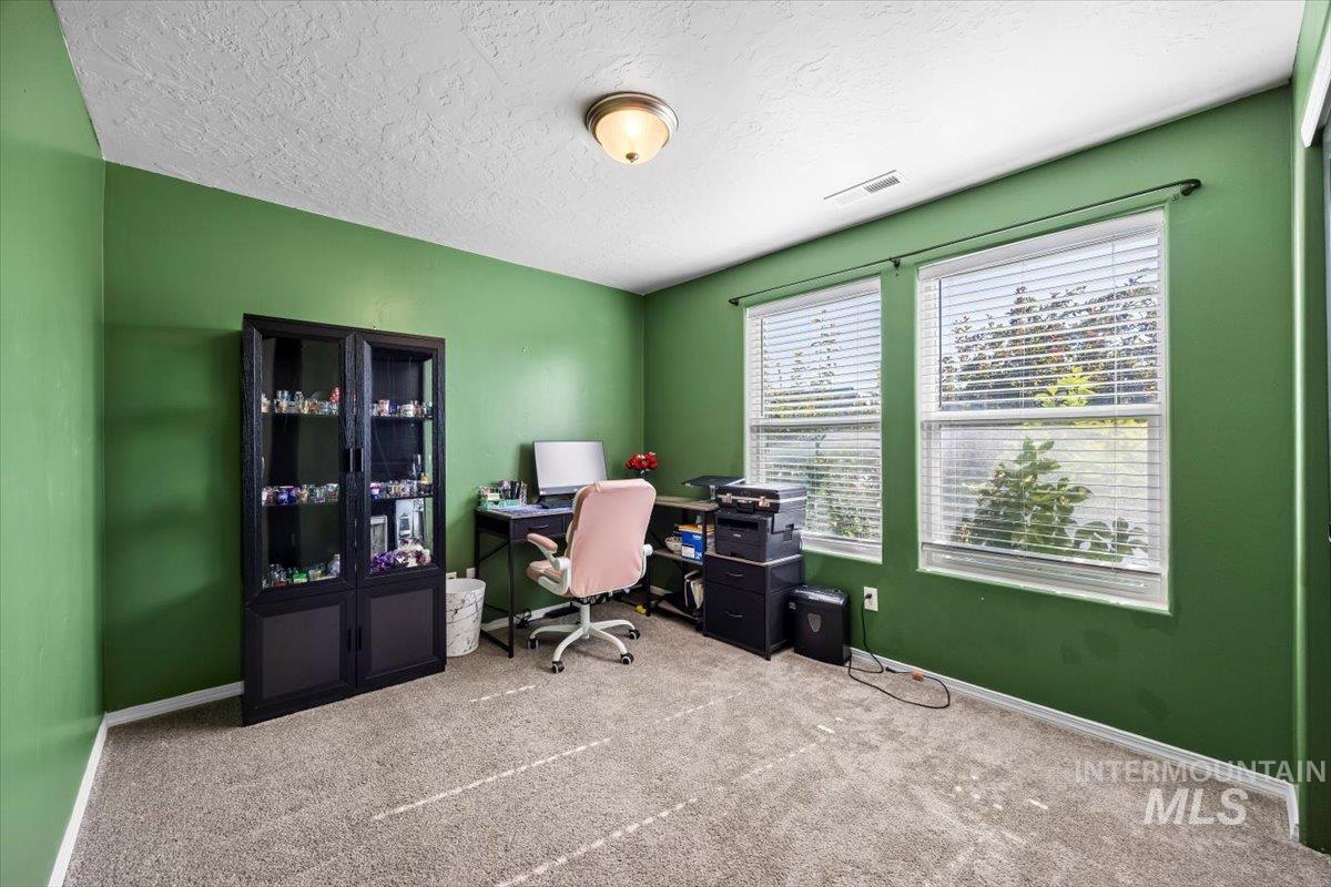 Carpeted office space featuring a textured ceiling and baseboards