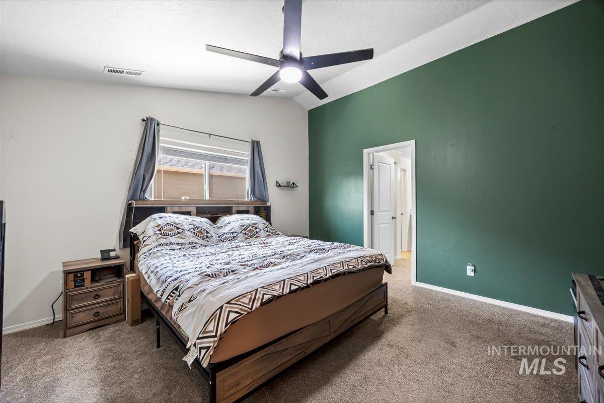 Bedroom featuring carpet flooring, lofted ceiling, ceiling fan, and a textured ceiling