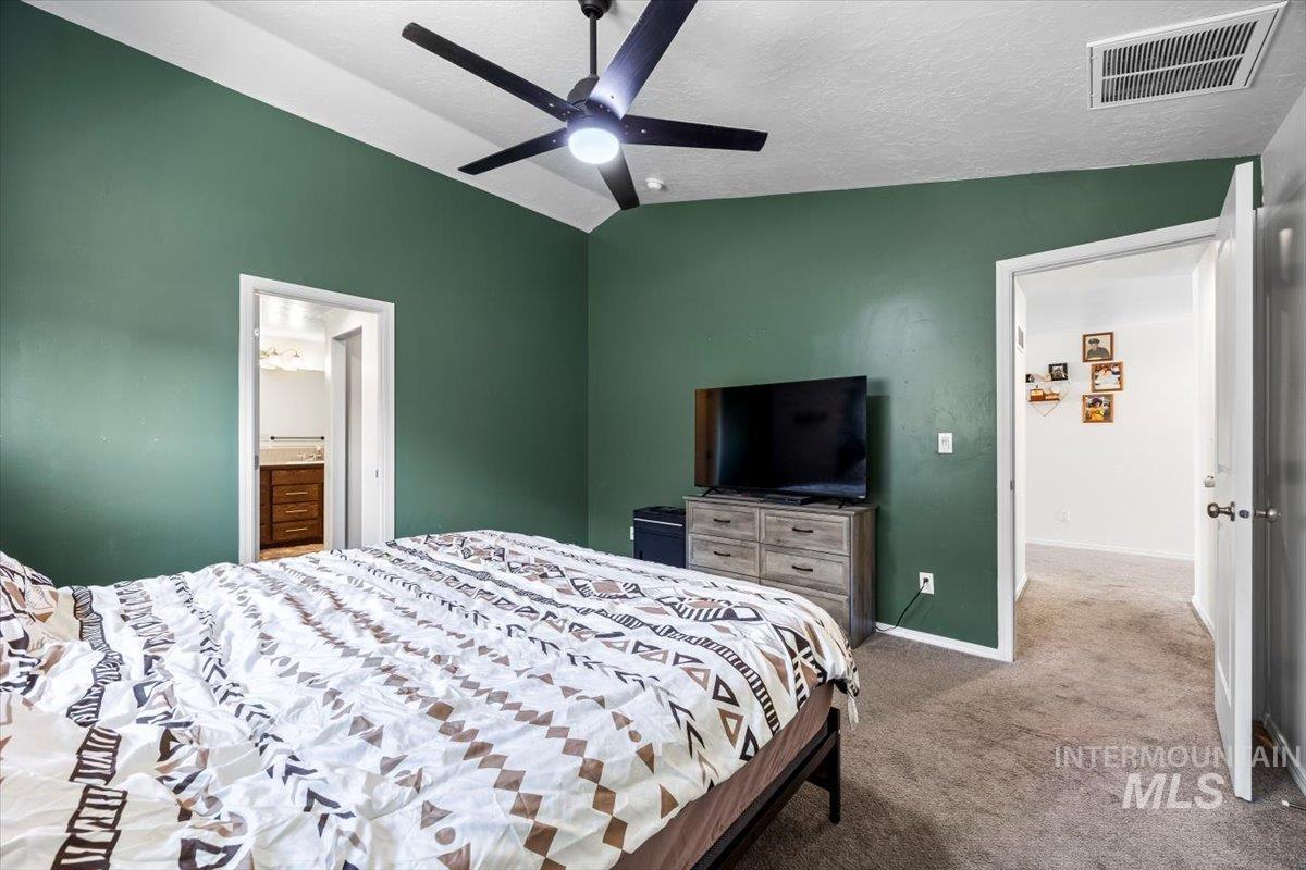 Bedroom featuring vaulted ceiling, carpet, a textured ceiling, and ceiling fan