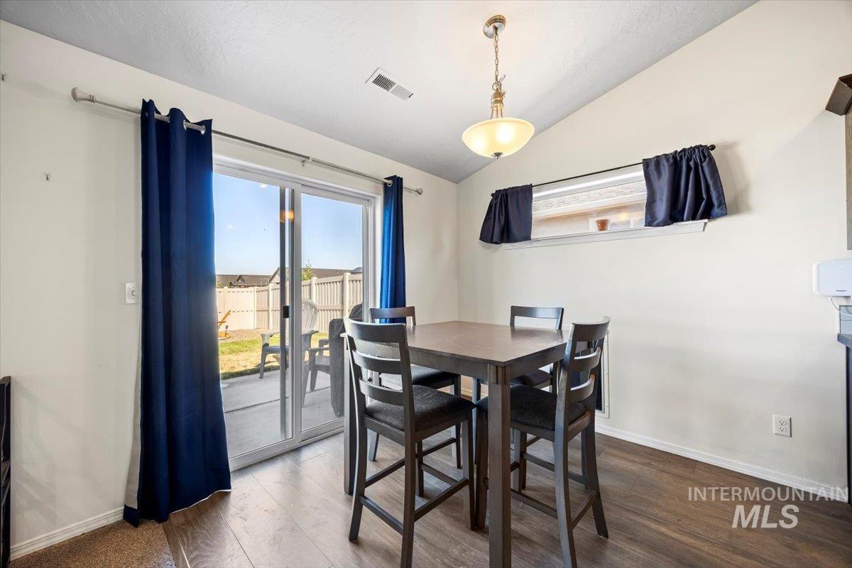 Dining area with plenty of natural light, vaulted ceiling, and dark wood finished floors
