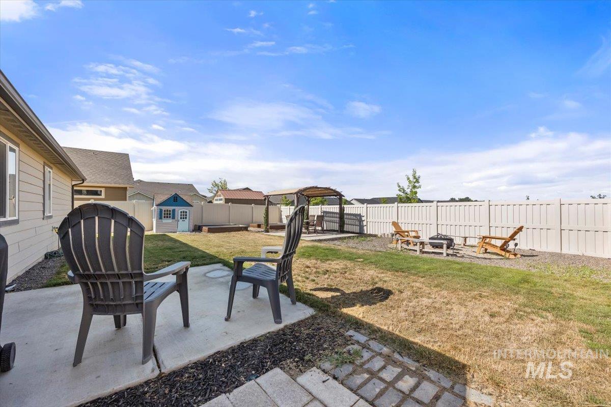 Fenced backyard with a fire pit, a shed, and a patio