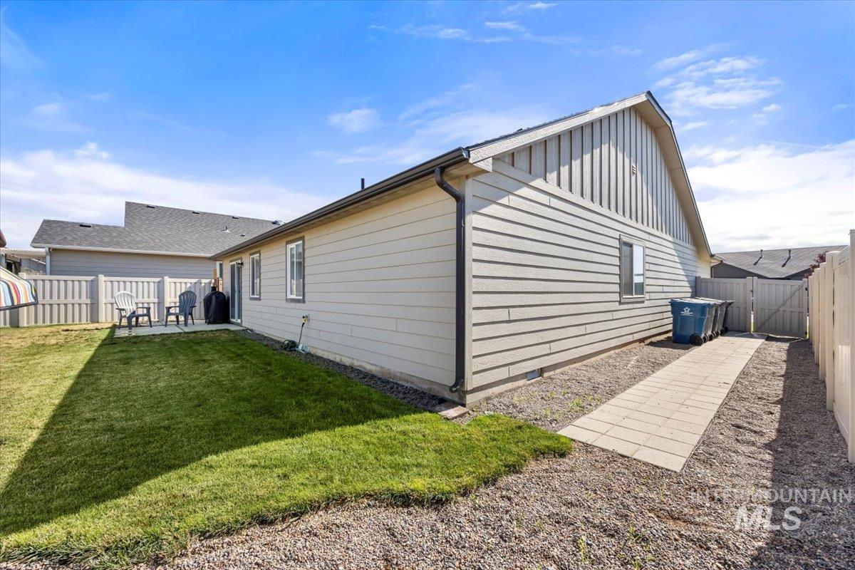 Back of property with board and batten siding, a fenced backyard, and a patio