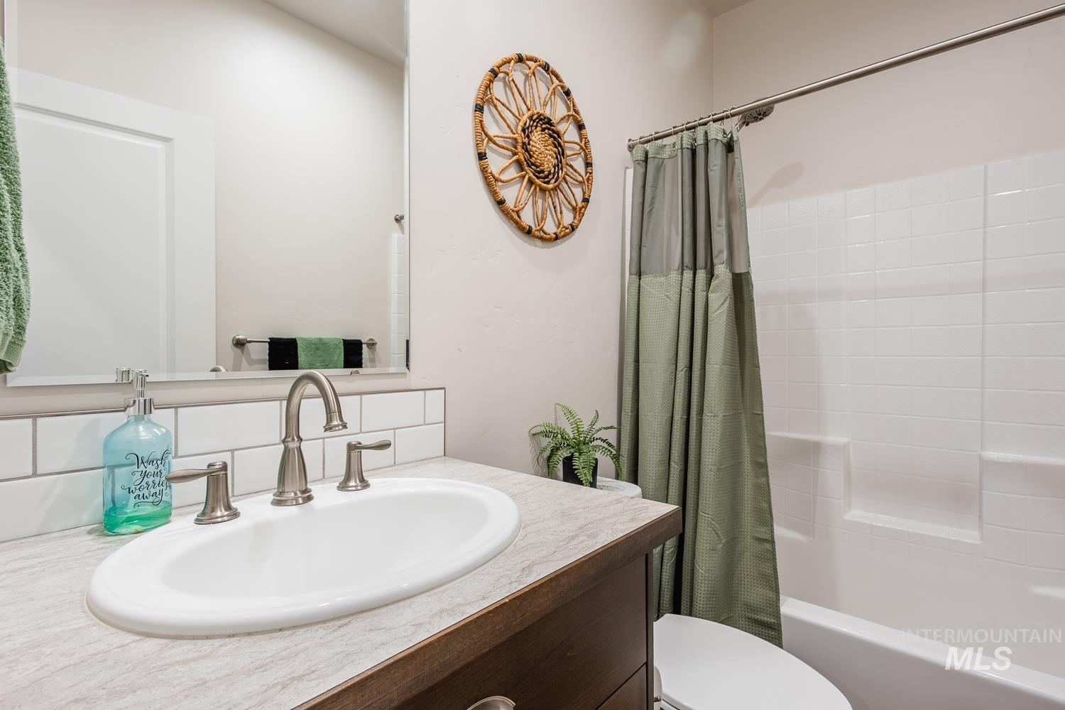 Bathroom with shower / tub combo, vanity, and decorative backsplash