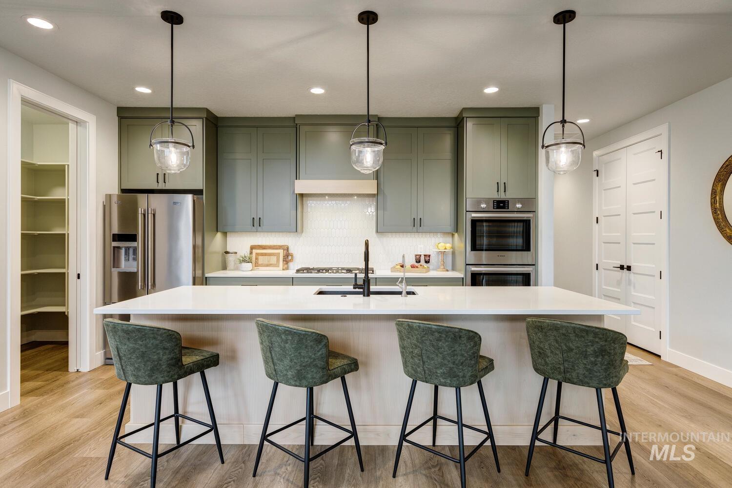 Kitchen with backsplash, decorative light fixtures, stainless steel appliances, a kitchen bar, and recessed lighting
