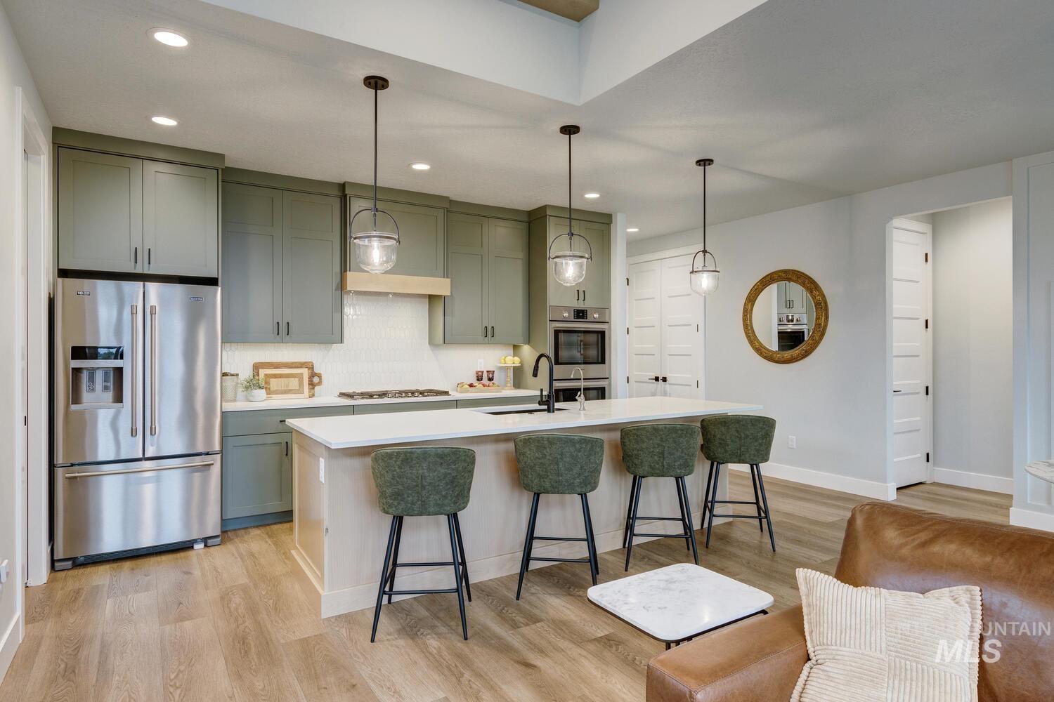 Kitchen with appliances with stainless steel finishes, decorative backsplash, decorative light fixtures, a breakfast bar area, and an island with sink