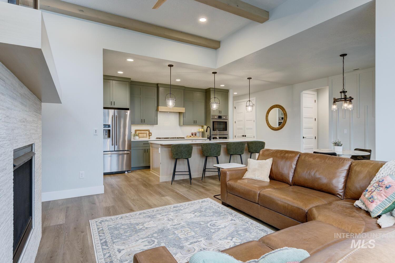 Living area with light wood-style floors, a stone fireplace, recessed lighting, and beamed ceiling