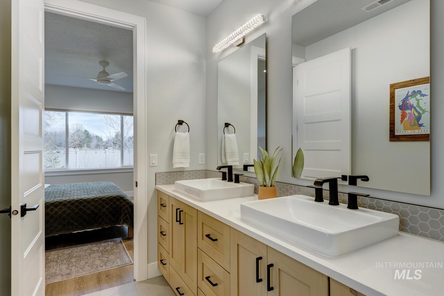 Bathroom featuring double vanity, connected bathroom, and ceiling fan