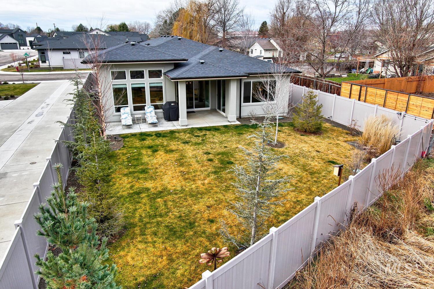 Rear view of house with a fenced backyard, a shingled roof, a patio, and a residential view
