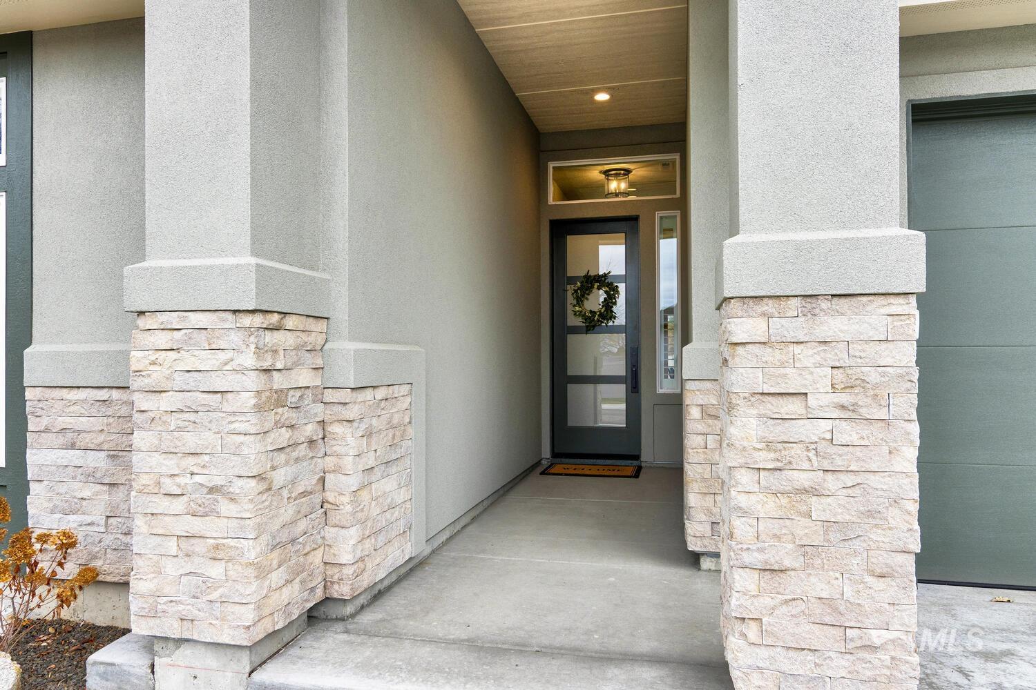 Property entrance with stucco siding, stone siding, and a porch