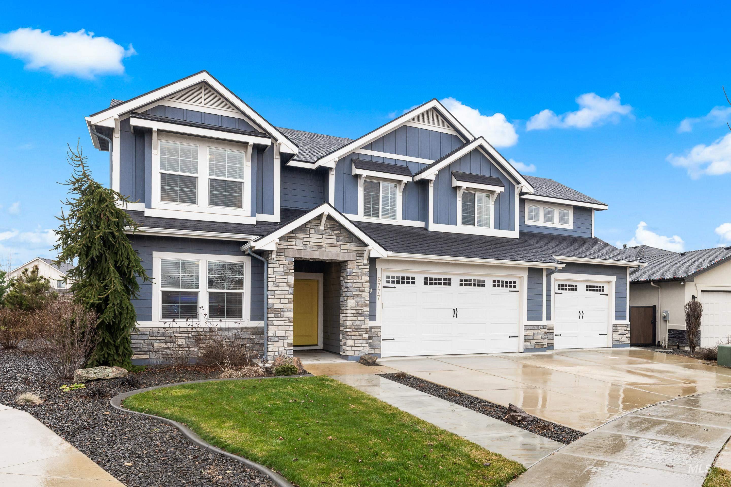 Craftsman-style home with stone siding, board and batten siding, driveway, and a garage