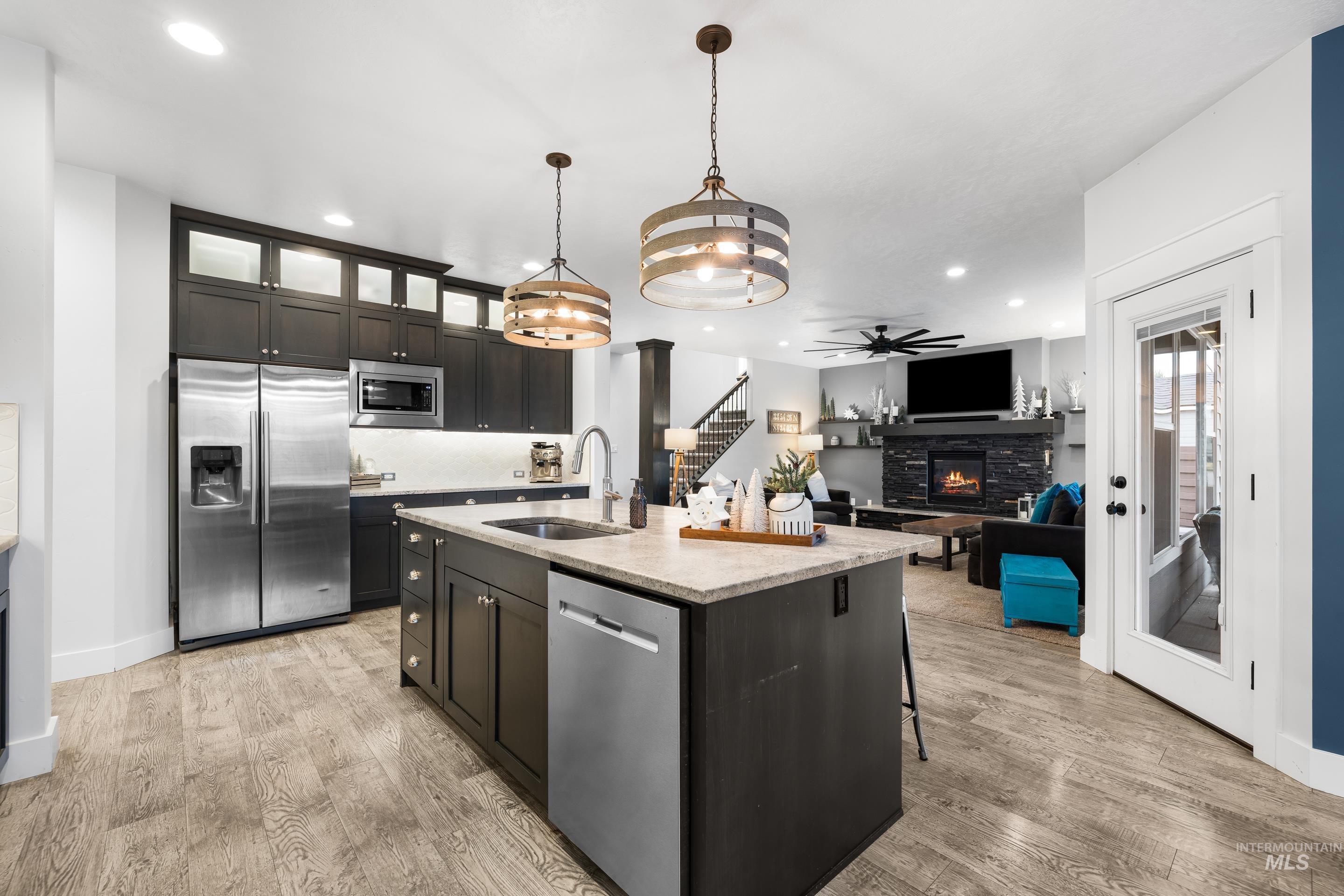 Kitchen with recessed lighting, stainless steel appliances, a fireplace, glass insert cabinets, and decorative light fixtures