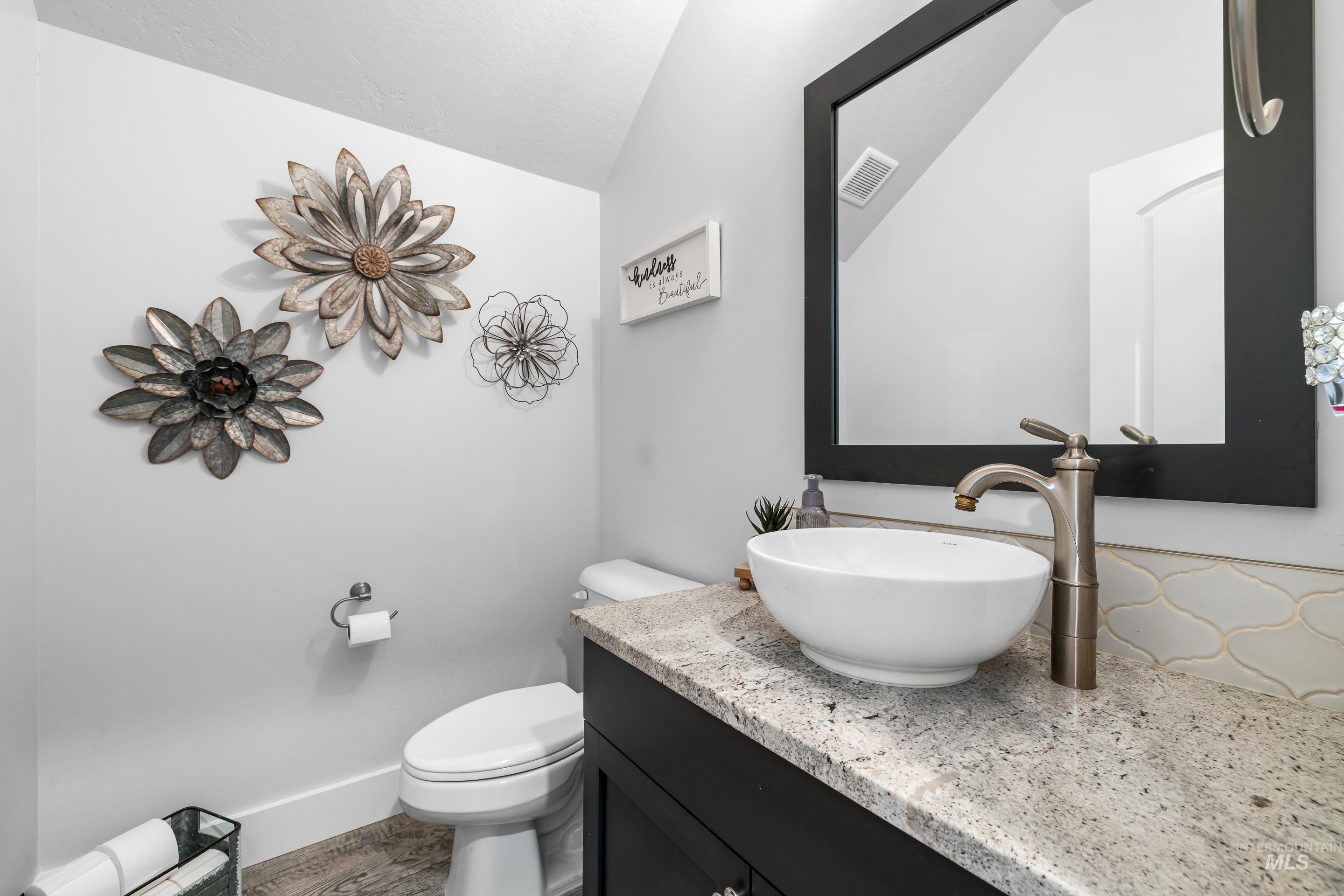 Half bathroom featuring vanity and vaulted ceiling