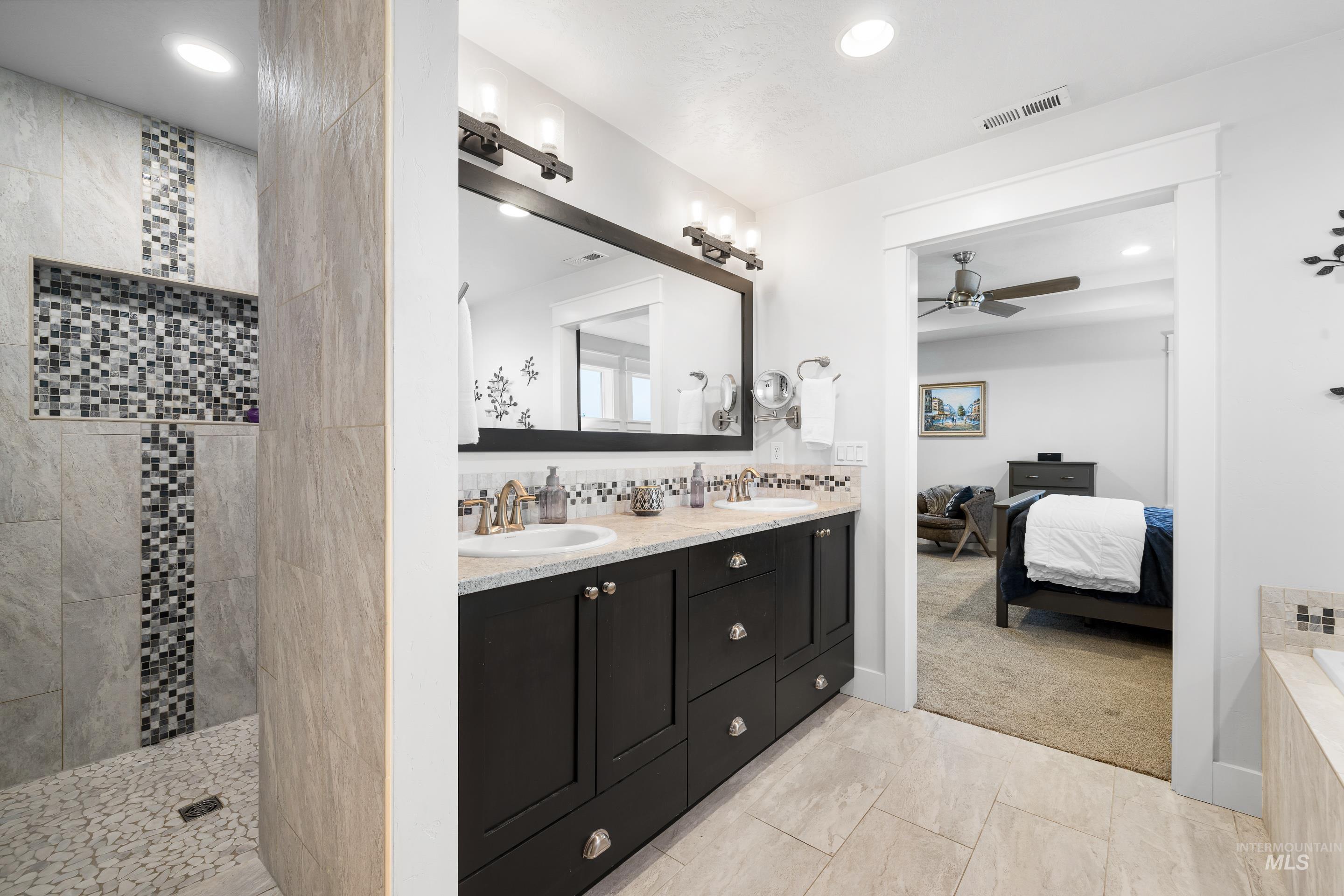 Ensuite bathroom featuring double vanity, a ceiling fan, and a walk in shower