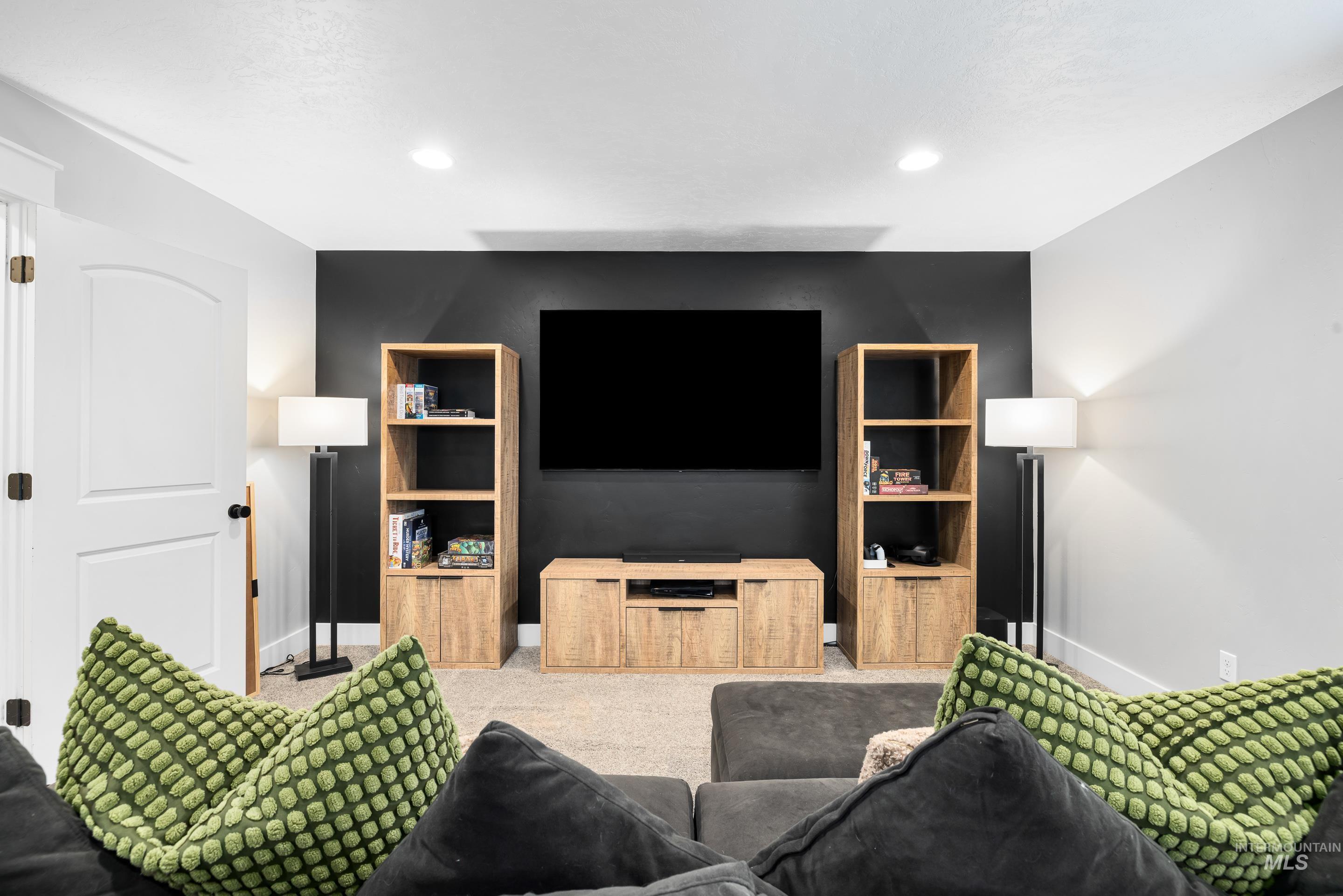 Carpeted living room with built in shelves and recessed lighting