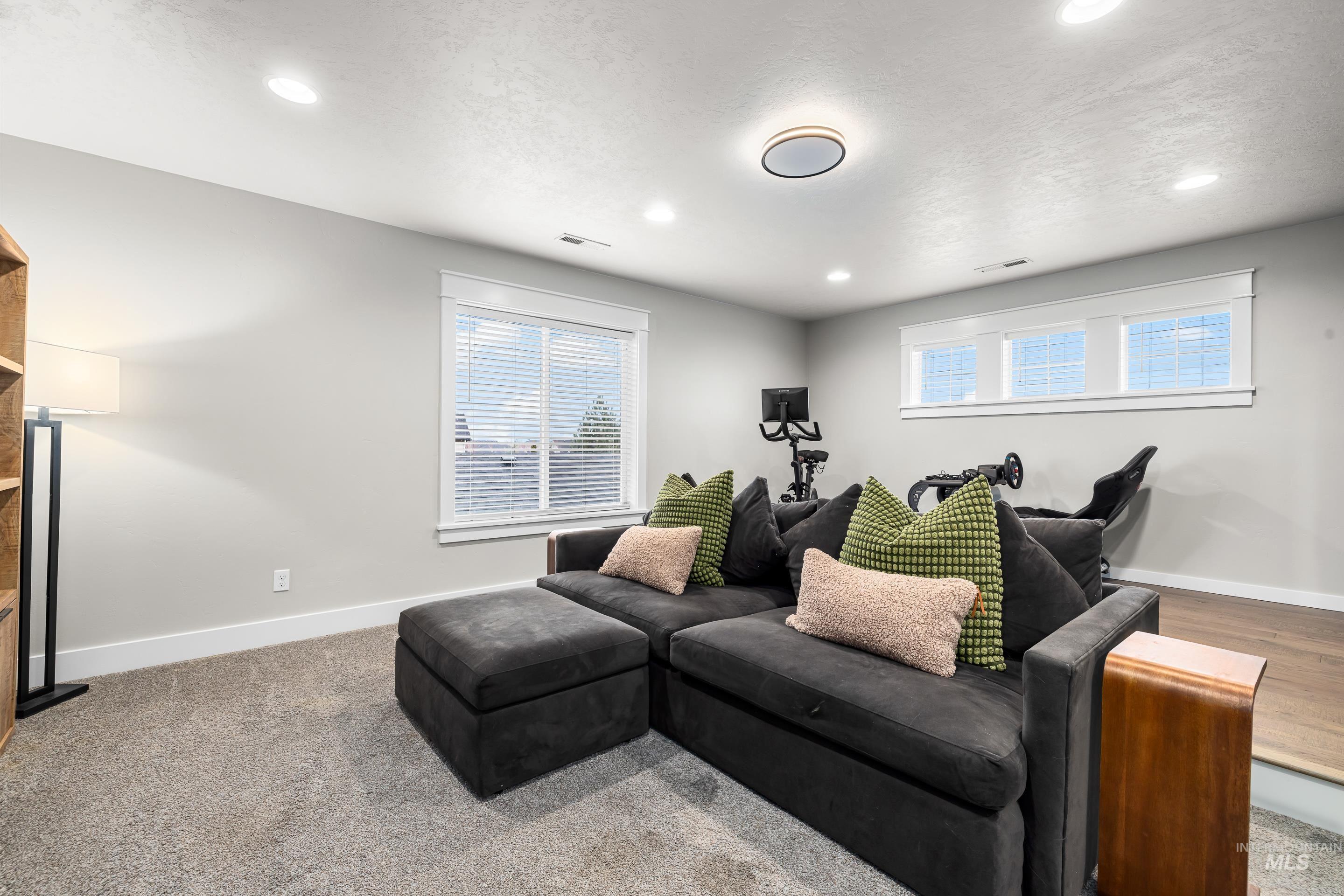 Living area with a textured ceiling, recessed lighting, and light carpet