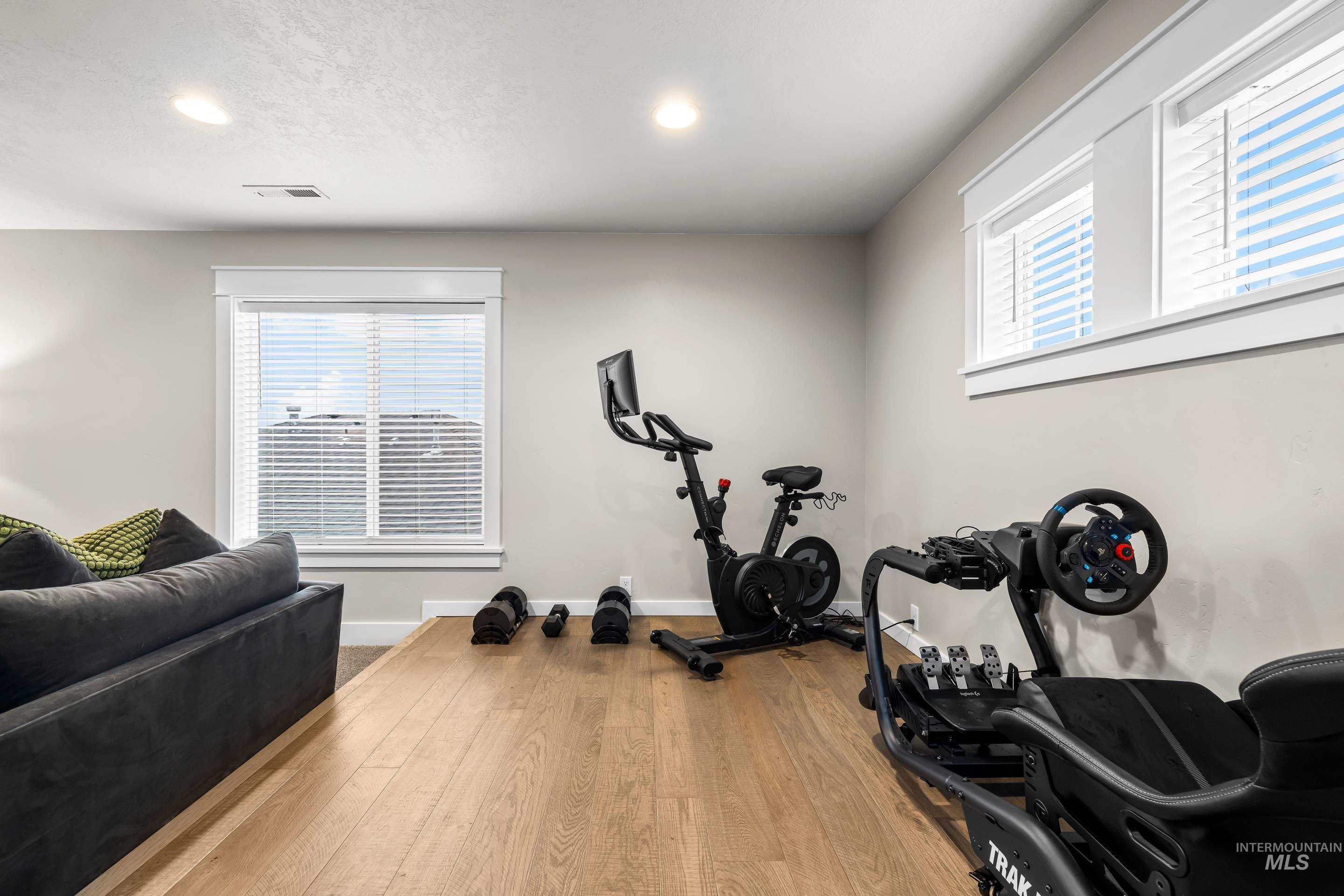 Workout room featuring healthy amount of natural light, hardwood / wood-style floors, recessed lighting, and a textured ceiling
