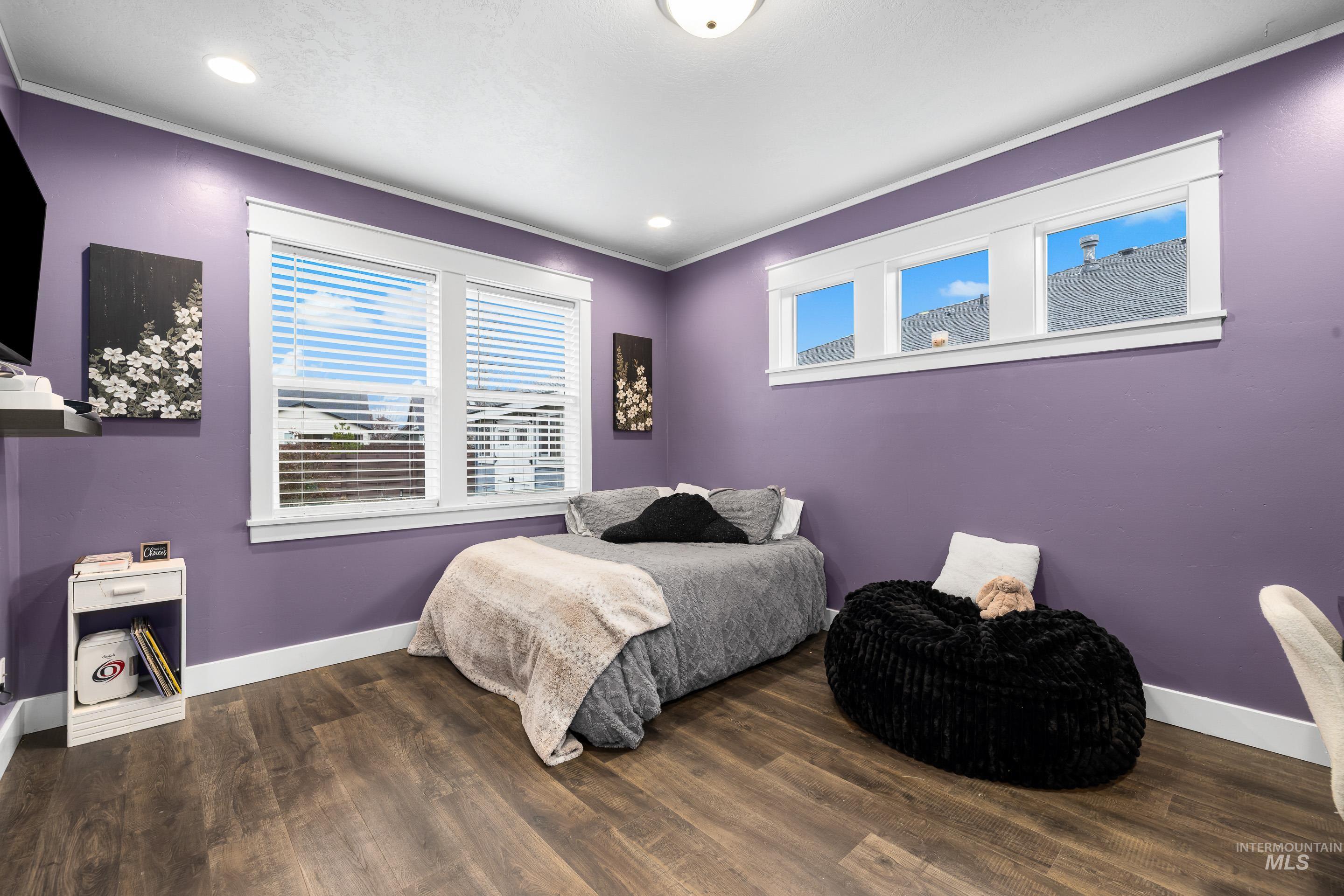 Bedroom with dark wood-style flooring and crown molding
