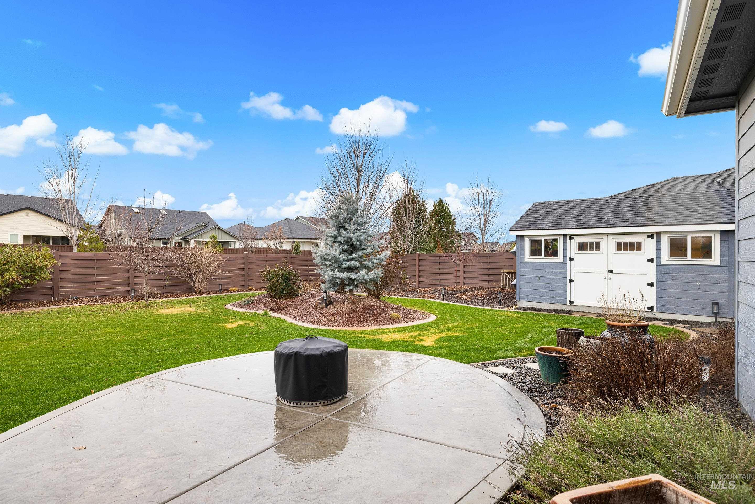 Fenced backyard featuring a patio area, an outdoor structure, and a residential view
