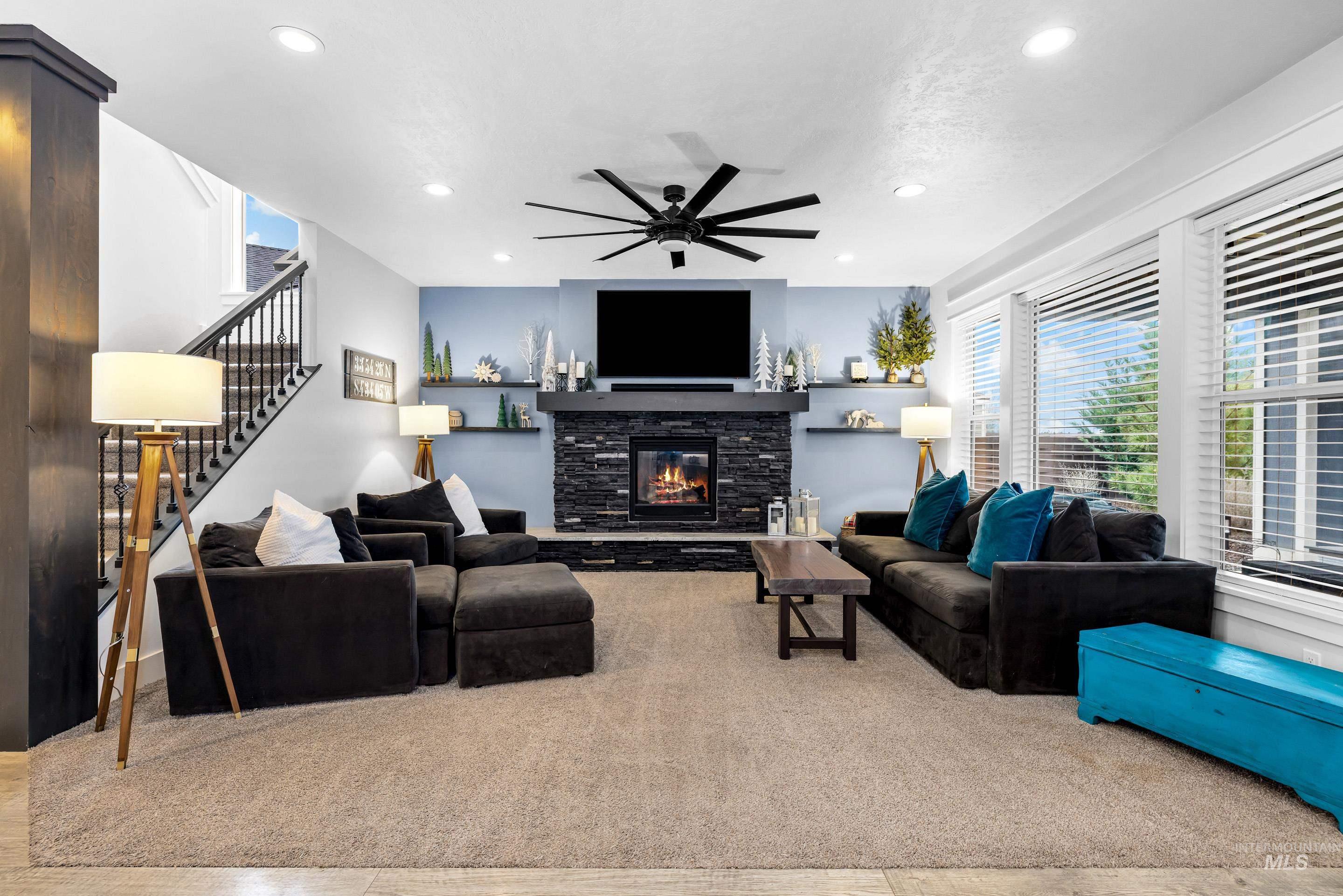 Carpeted living area featuring a fireplace, stairs, a ceiling fan, and recessed lighting