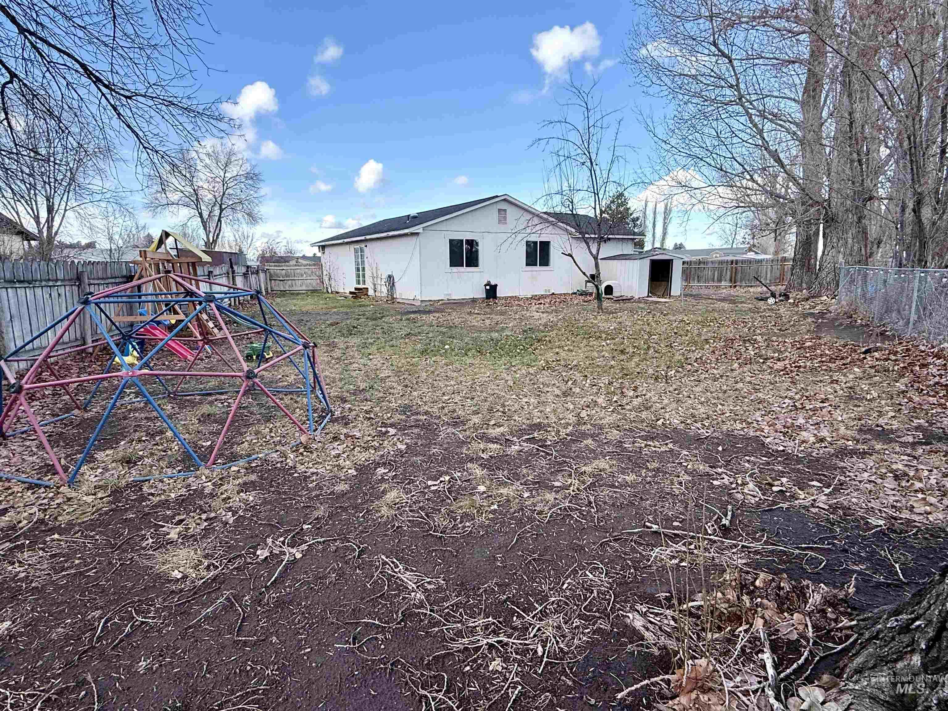 Fenced backyard featuring a playground and an outdoor structure