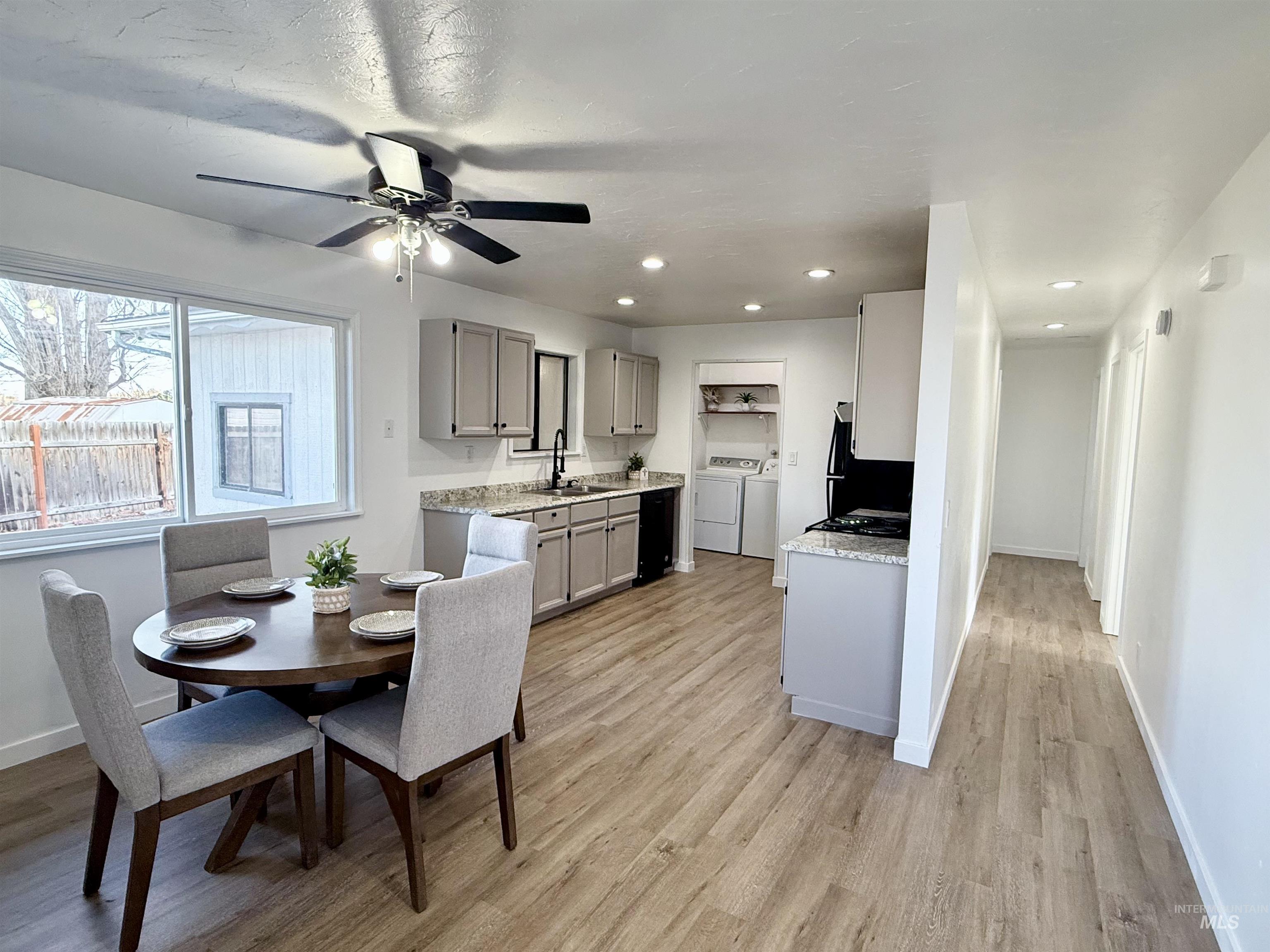 Kitchen with gray cabinets, washing machine and clothes dryer, light wood-style flooring, ceiling fan, and fridge