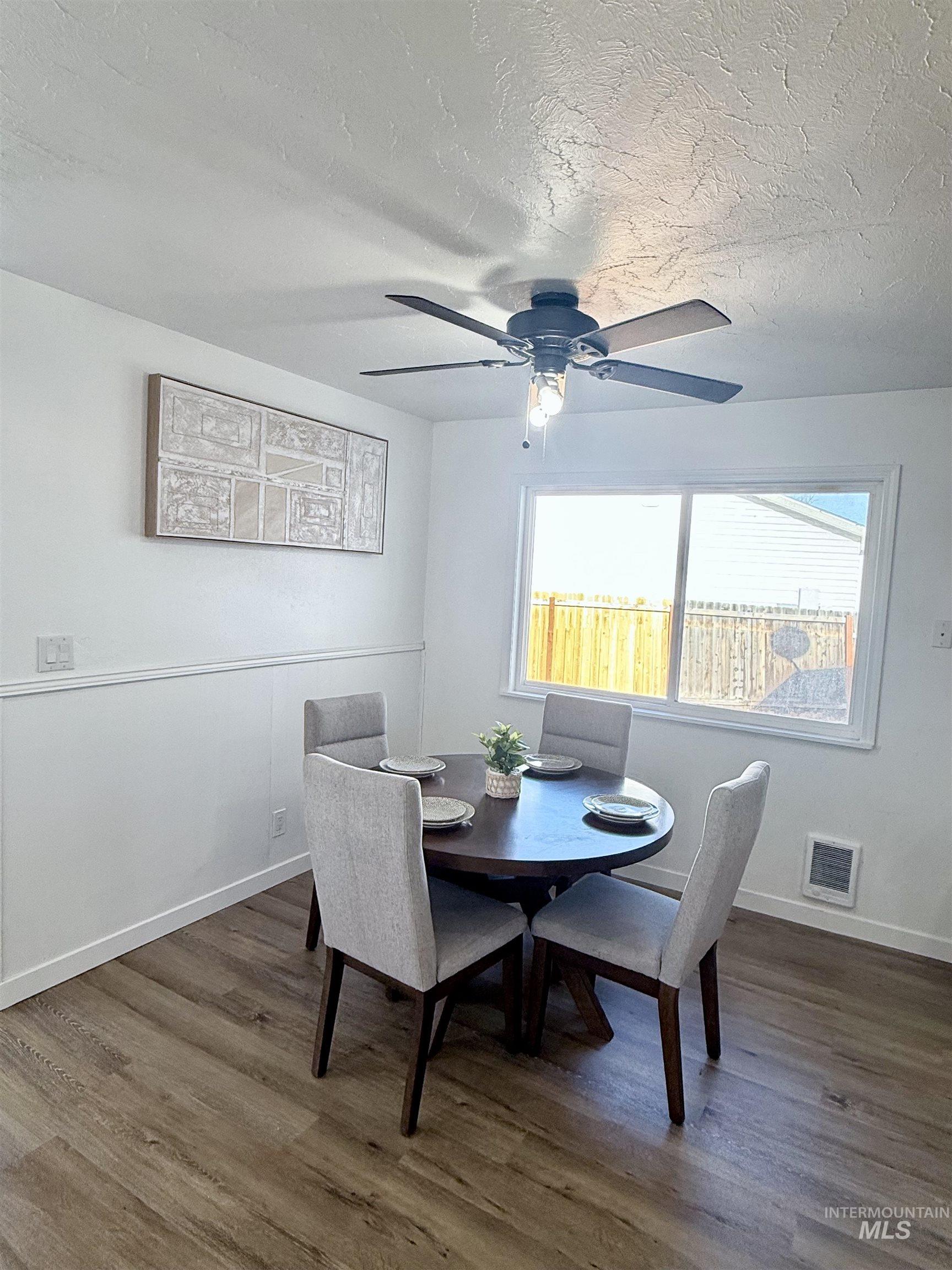 Dining area with dark wood-type flooring, a textured ceiling, and ceiling fan
