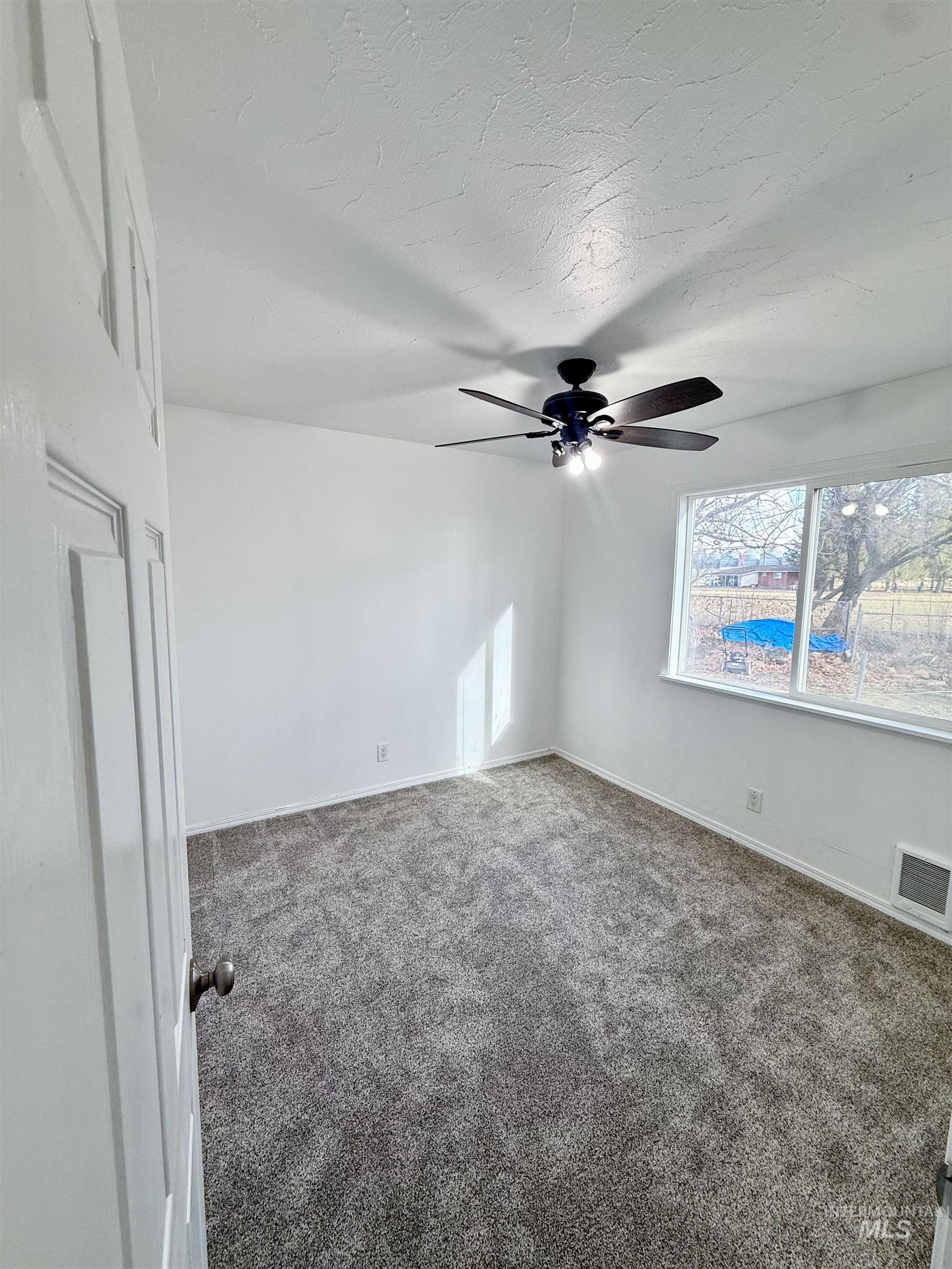 Spare room with carpet flooring, a textured ceiling, and a ceiling fan