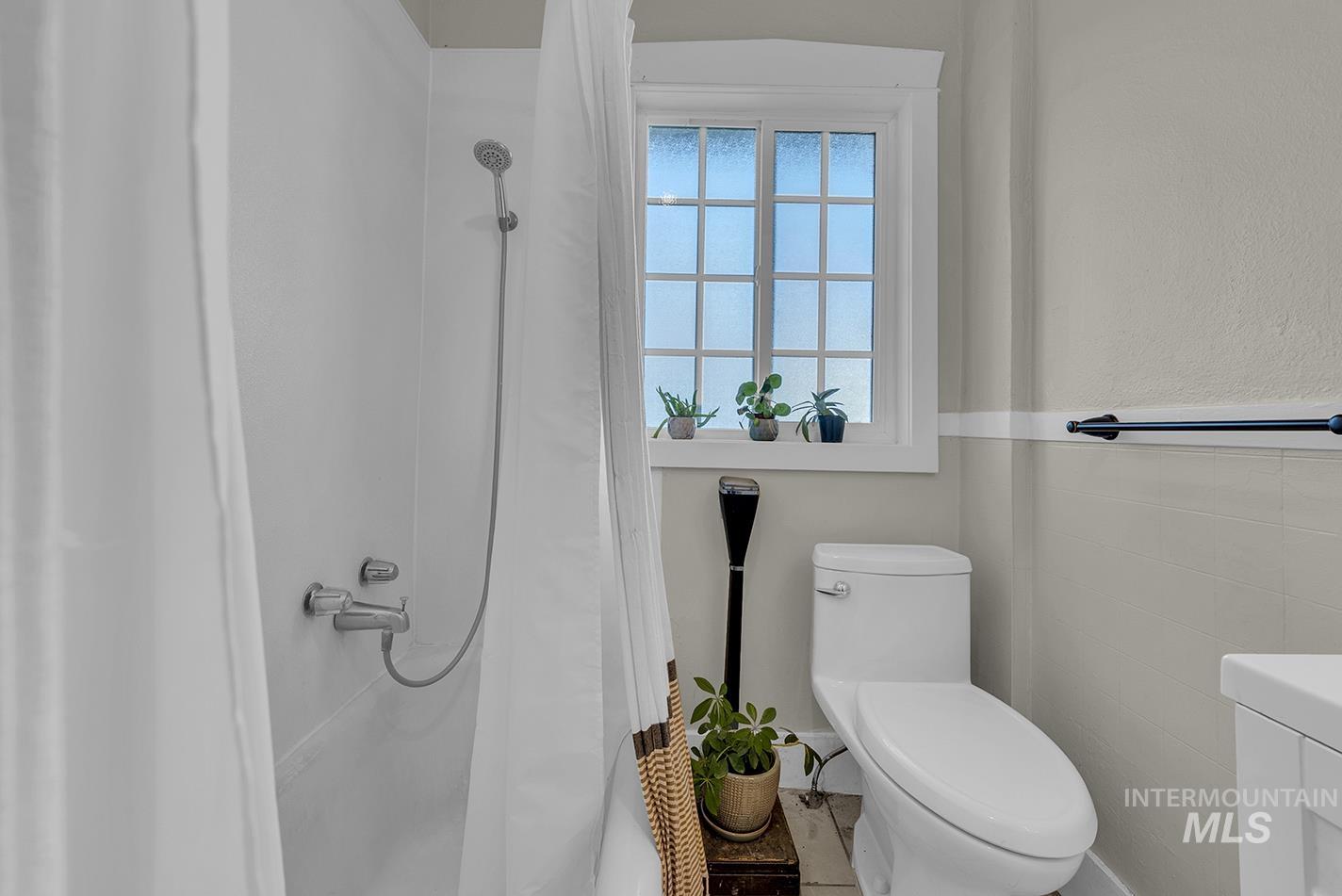 Bathroom featuring a shower with shower curtain, vanity, and a wainscoted wall