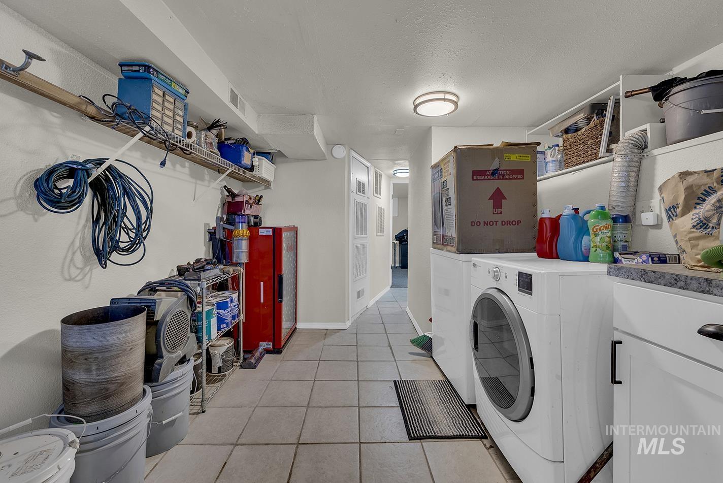 Laundry area featuring light tile patterned floors, a textured ceiling, and separate washer and dryer
