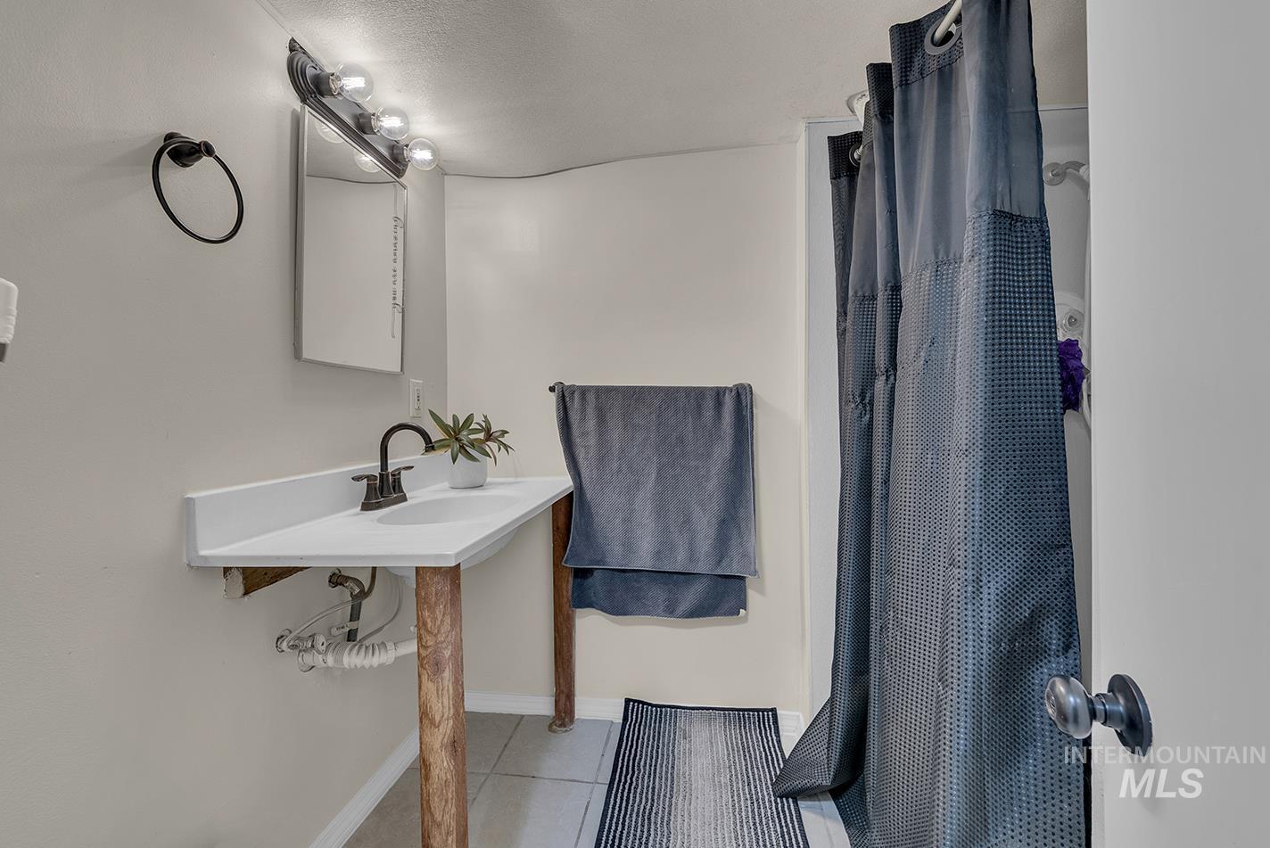 Full bath with a shower with shower curtain and tile patterned floors