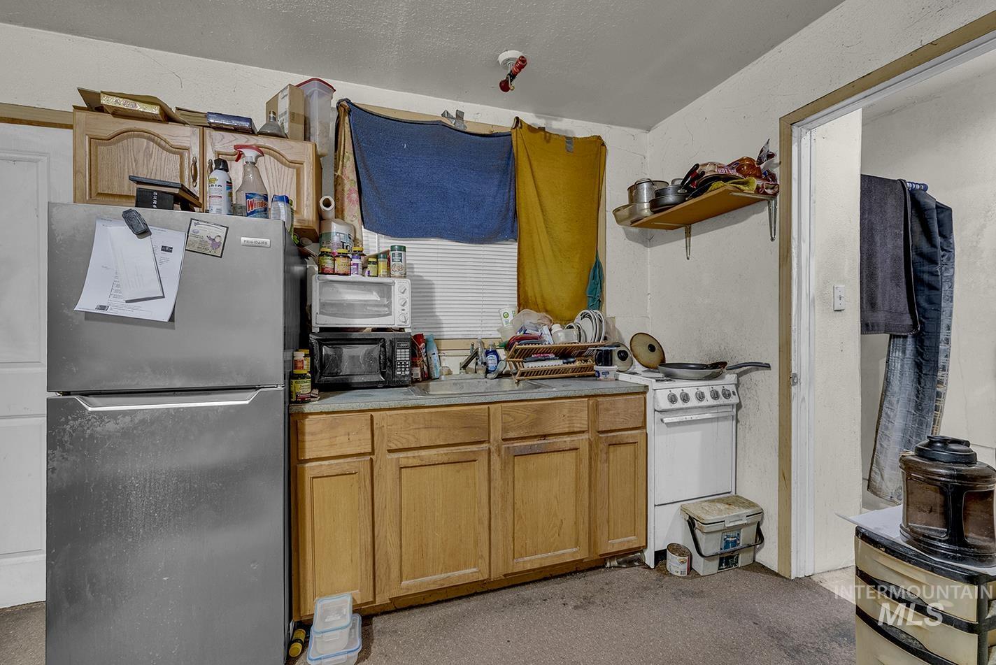 Kitchen featuring freestanding refrigerator, light countertops, open shelves, electric range, and a textured ceiling
