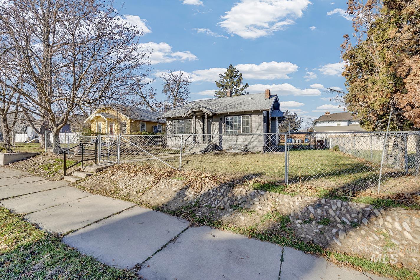 Bungalow-style home featuring a fenced front yard, a chimney, and a gate