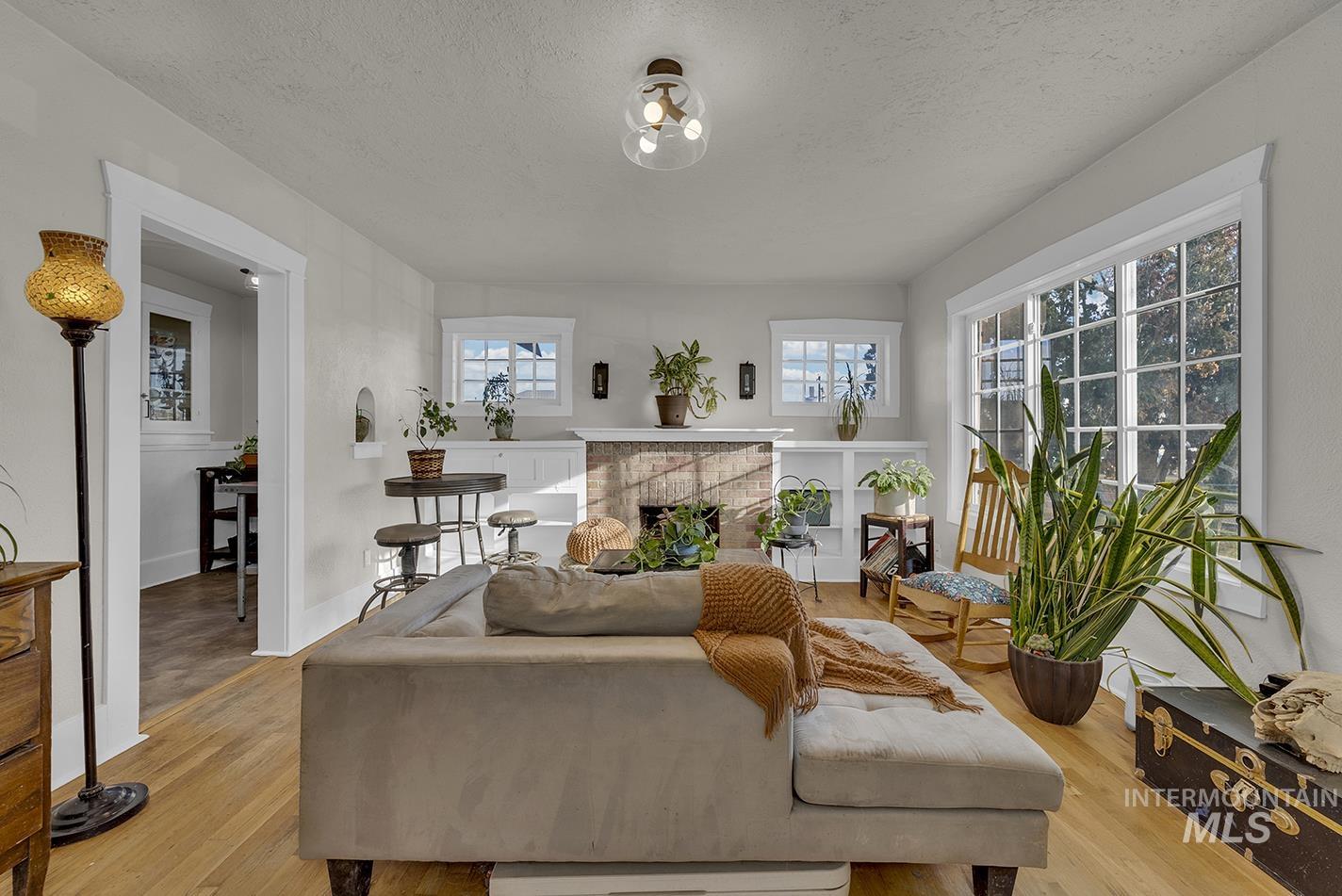 Living room with a fireplace, a textured ceiling, and light wood-type flooring