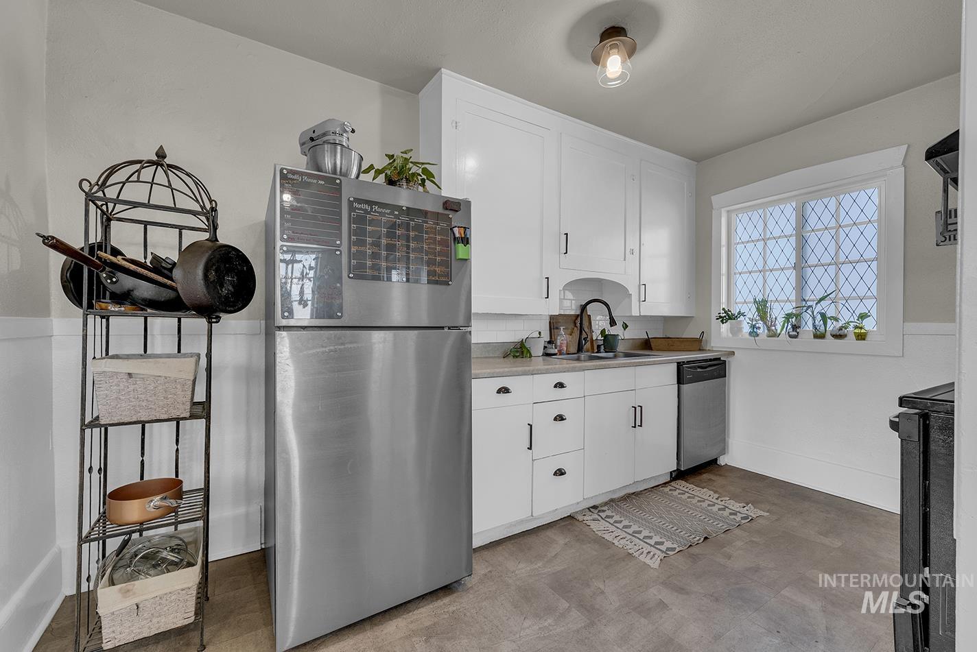 Kitchen featuring appliances with stainless steel finishes, white cabinets, light countertops, and light floors
