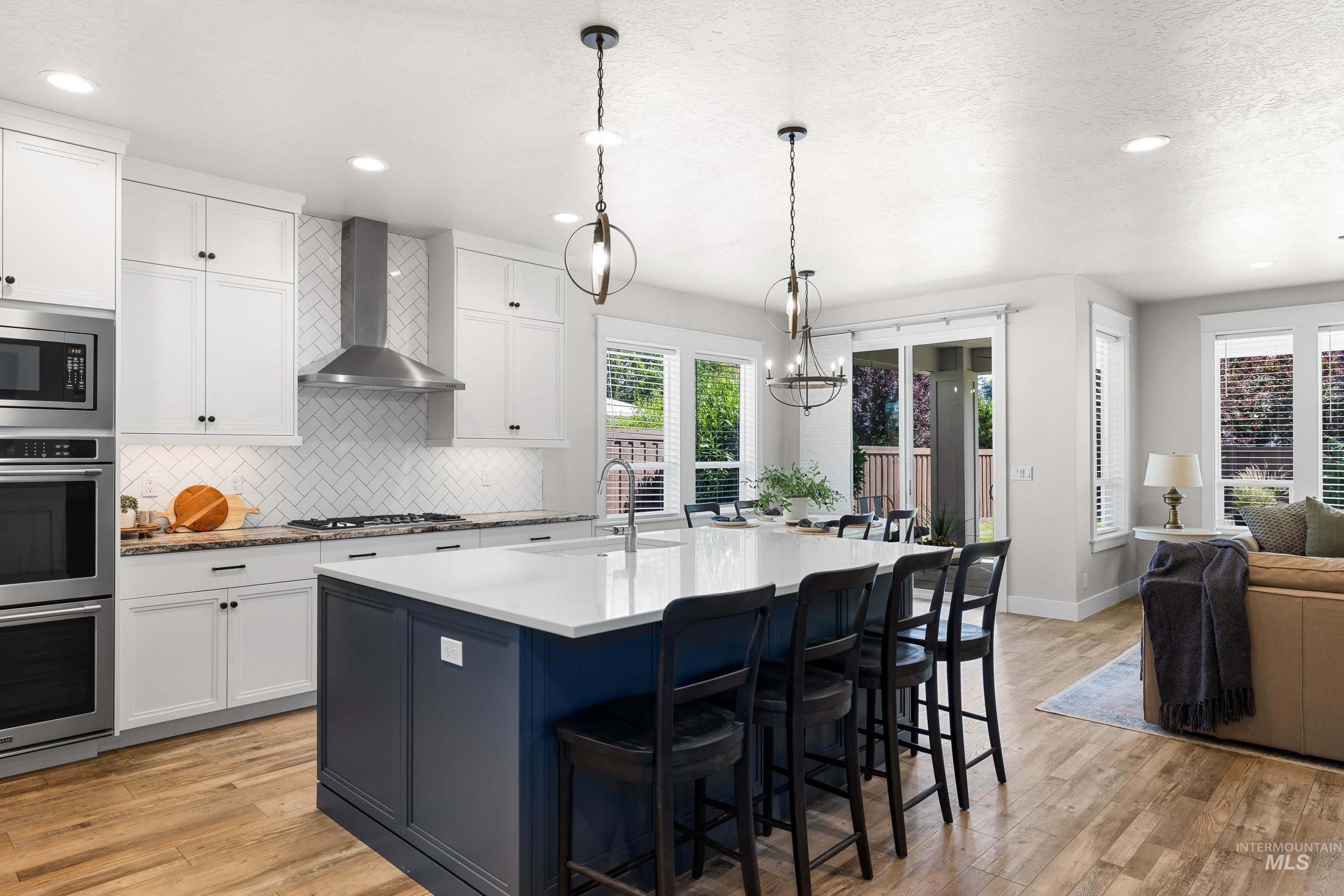 Kitchen featuring wall chimney range hood, appliances with stainless steel finishes, healthy amount of natural light, tasteful backsplash, and recessed lighting