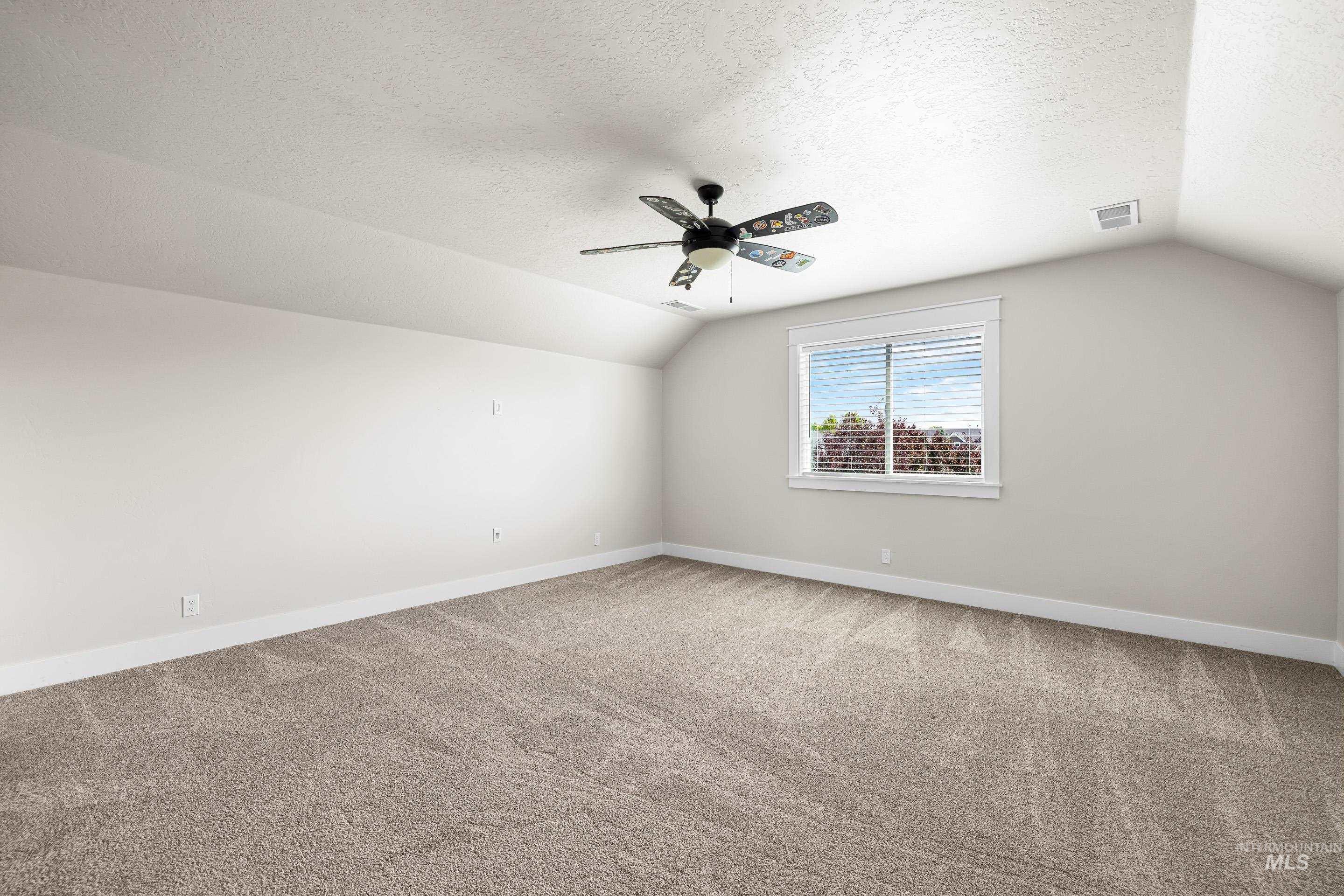 Bonus room featuring vaulted ceiling, carpet floors, a textured ceiling, and a ceiling fan