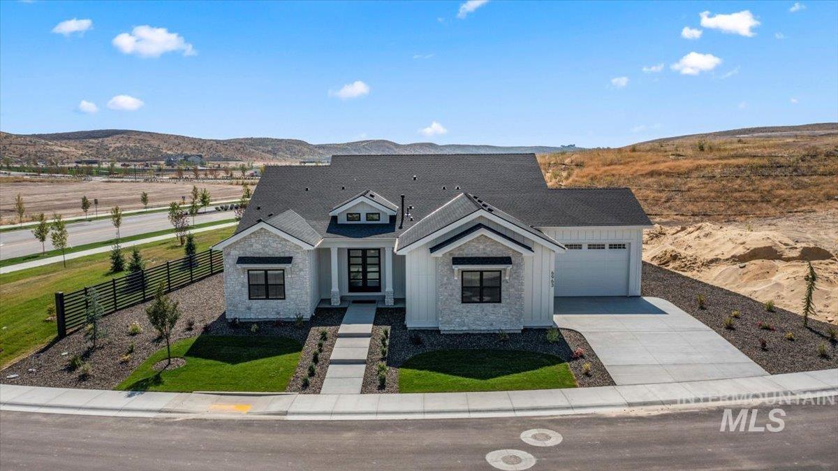 Modern farmhouse style home featuring concrete driveway, stone siding, a mountain view, and an attached garage