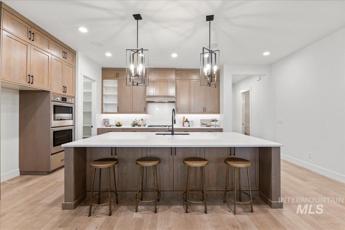 Kitchen featuring recessed lighting, hanging light fixtures, a spacious island, a breakfast bar, and light wood finished floors