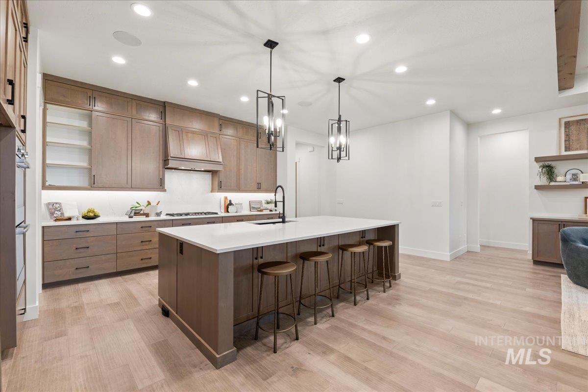 Kitchen with open shelves, recessed lighting, a kitchen breakfast bar, pendant lighting, and a spacious island