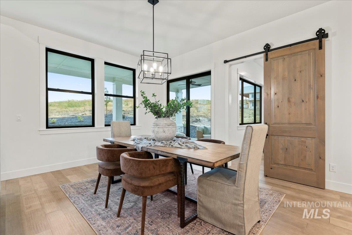Dining area featuring light wood-type flooring, a chandelier, and a barn door