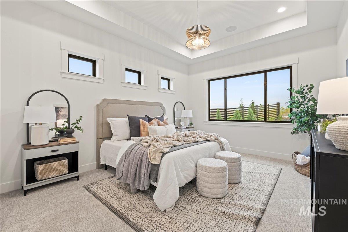 Bedroom featuring light colored carpet and a raised ceiling