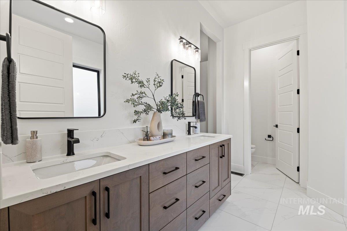 Full bathroom featuring double vanity and light marble finish flooring