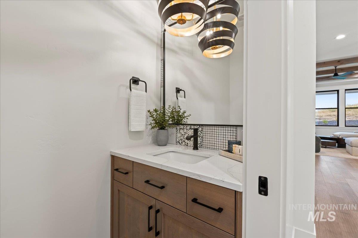 Bathroom featuring vanity, decorative backsplash, and beamed ceiling