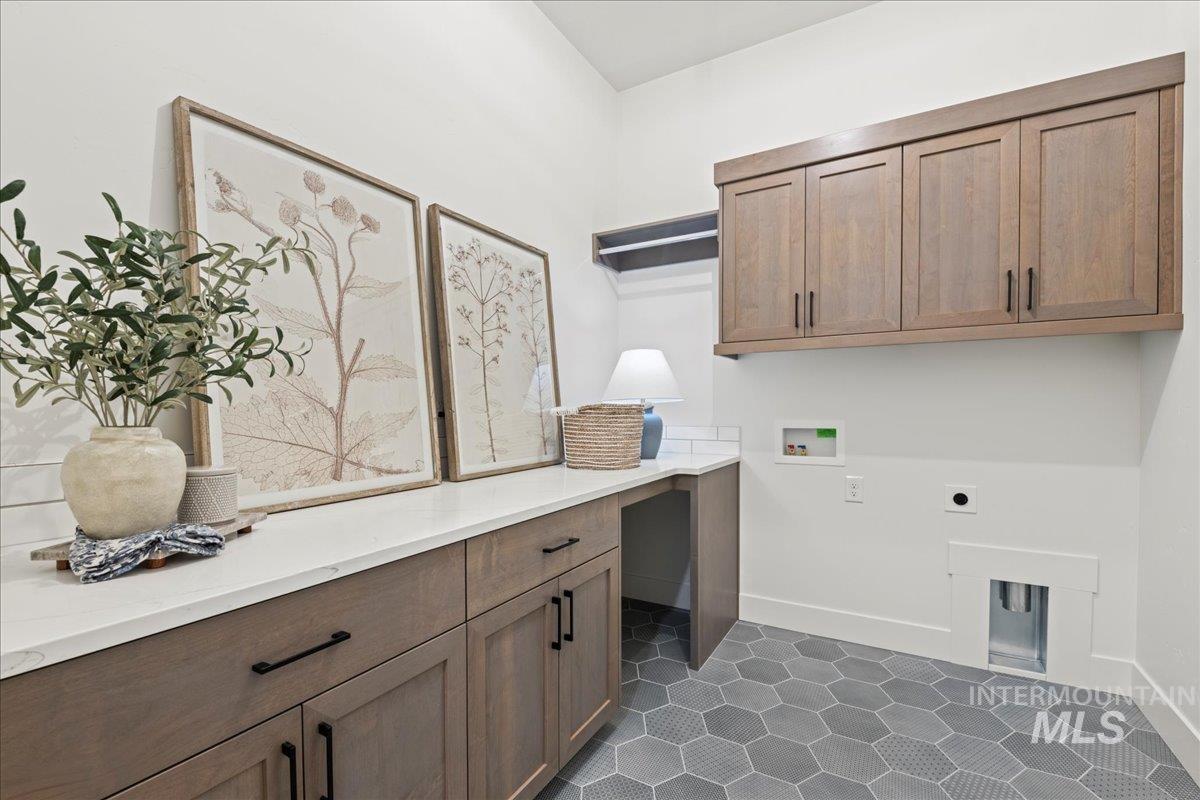 Laundry room featuring hookup for a washing machine, dark tile patterned flooring, electric dryer hookup, and cabinet space